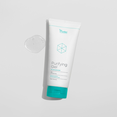 Tube mit Reinigungs-Gel auf weißem Hintergrund, daneben ein Tropfen des transparenten Gels.