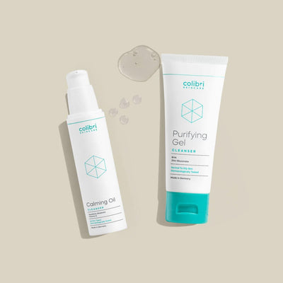 Zwei Kosmetikprodukte auf beigem Hintergrund: Eine Flasche "Calming Oil" und eine Tube "Purifying Gel".