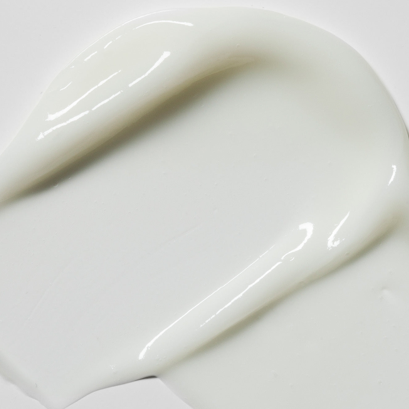 Nahaufnahme von weißer Creme, die gleichmäßig auf einer glatten Oberfläche verteilt ist.