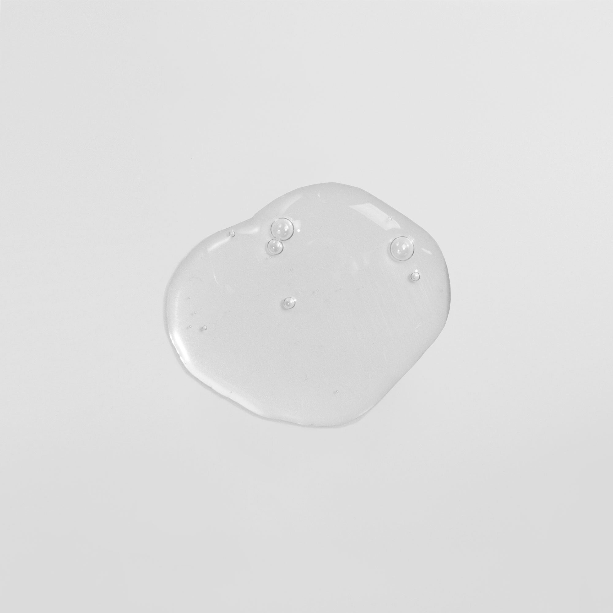 Transparenter Gel-Tropfen mit Luftblasen auf weißem Hintergrund.