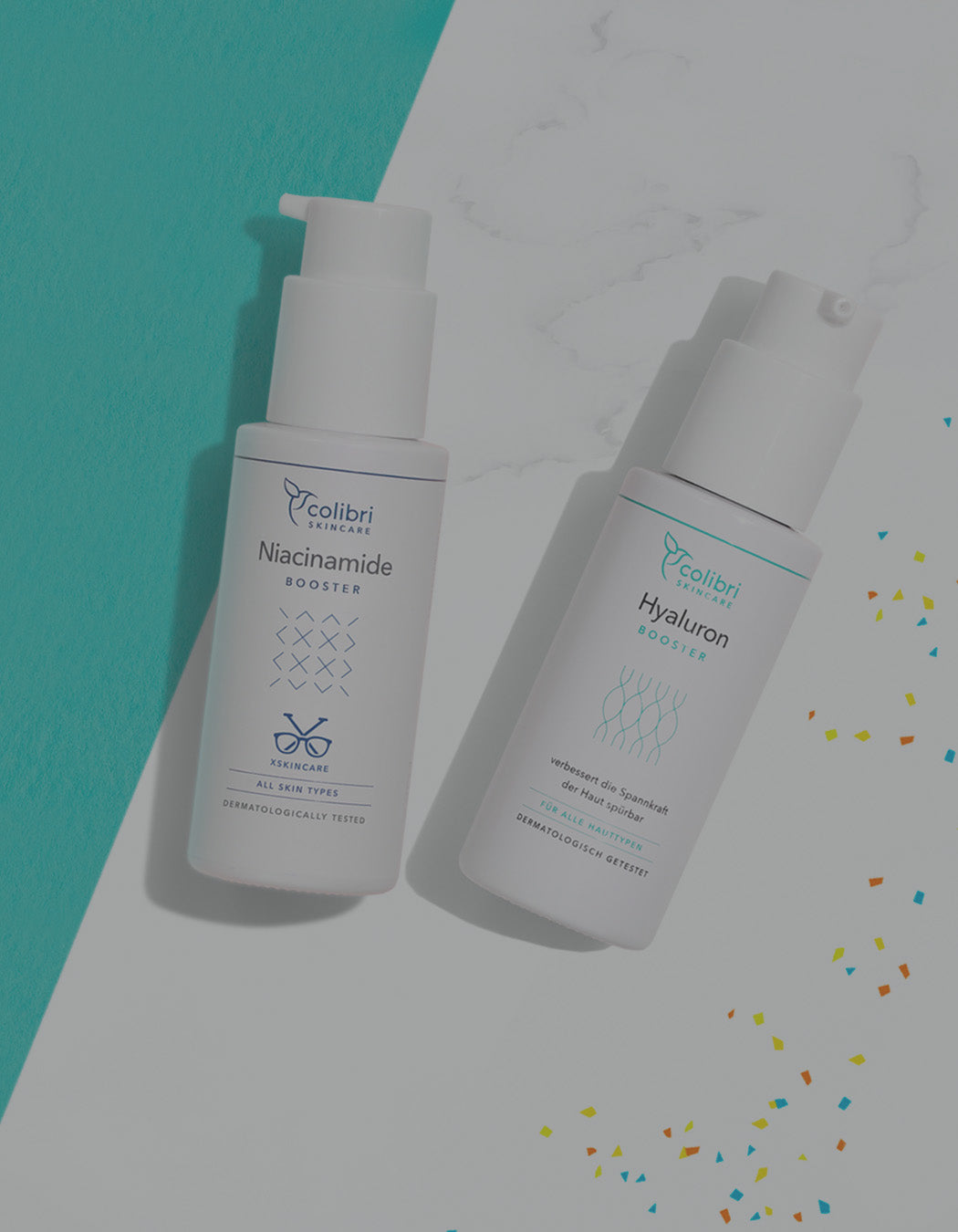 Zwei Flaschen Hautpflegeprodukte von Colibri Skincare auf blauem und weißem Hintergrund mit buntem Konfetti.
