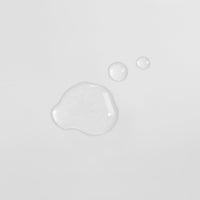 Drei Wassertröpfchen auf einer weißen Oberfläche, zwei kleinere oben rechts und ein größeres links unten.